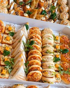 several trays filled with different types of sandwiches and appetizers on white doily