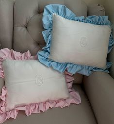 two pillows sitting on top of a couch next to a pillow with ruffled edges