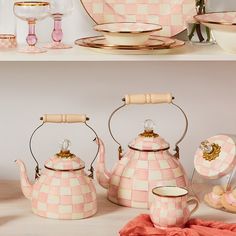 pink and white checkered tea set with gold trimmings on the top, next to other items