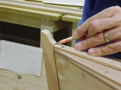 a person working on a piece of wood with a small wooden object in the foreground