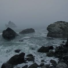 foggy day at the beach with rocks and water