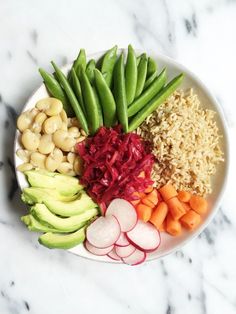 a white plate topped with veggies and rice next to sliced up carrots