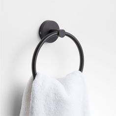 a towel hanging on the wall next to a black metal holder with a white towel