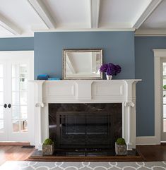 a living room filled with furniture and a fire place under a mirror on top of a mantle