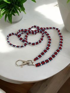 a red, white and blue beaded lanyard on a table next to a potted plant