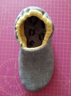 a pair of baby shoes sitting on top of a cutting board next to a ruler