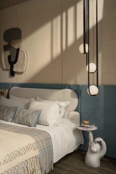 a bed with white sheets and pillows next to a lamp on top of a table