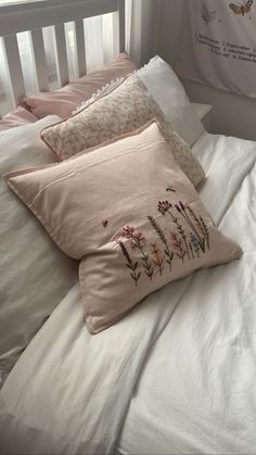 three pillows on top of a bed with white sheets