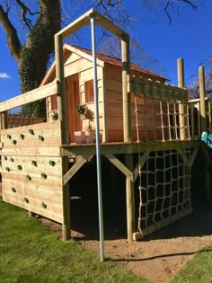 a wooden play house with a net on the roof and stairs leading up to it