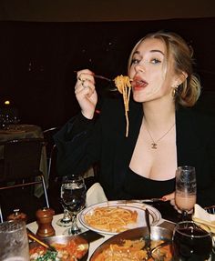 a woman sitting at a table eating spaghetti