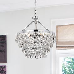 a chandelier hanging from the ceiling in a room with white walls and windows