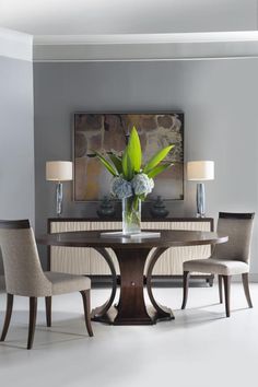 a dining room table with chairs around it and a vase filled with flowers on top