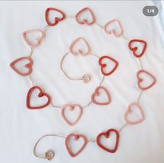 red and white heart shaped beads are arranged on a white sheet with a silver chain