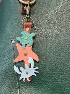 a close up of a keychain on a leather surface with a crab and starfish