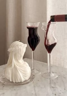 two wine goblets filled with red and white liquid are sitting on a marble table