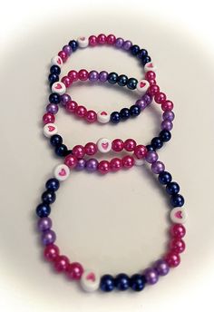 three bracelets with different colored beads on white background, one is purple and the other is black