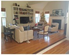 a living room filled with furniture and a christmas tree in the corner on top of a hard wood floor