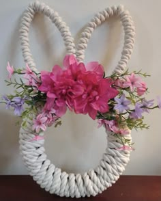 a white rope wreath with pink and purple flowers