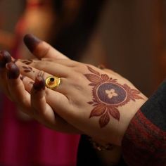 a woman's hand with a henna tattoo on her left wrist and gold ring