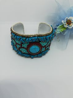 Beautiful and elegant bracelet in a slightly ethnic style, hand embroidered with a central turquoise cabochon and aulite gems. It is difficult and slow work, it took many hours of work from planning to realization of the final project. Each bead is individually hand sewn to create the final design. Inside the bracelet is covered in natural leather which gives a soft touch to the skin. This bracelet is comfortable to wear, goes perfectly with clothes of different colors. The colors used recall summer, the sea and the sun... The width of the bracelet is 4cm (1.6 inches). It has a brass plate inside that holds its shape and fits any wrist size. Wearing this bracelet will make you feel unique and special. Each piece is unique. If you would like a personalized bracelet in the colors of your cho Handwork Multicolor Bangle Jewelry, Traditional Handwork Bangle Jewelry, Unique Handmade Blue Bangle, Elegant Embroidered Jewelry For Festival, Elegant Embroidered Festival Jewelry, Bohemian Beaded Cuff Jewelry, Bohemian Embroidered Cuff Bracelet For Gift, Bohemian Embroidered Cuff Bracelet As Gift, Bohemian Adjustable Embellished Jewelry