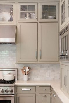 a kitchen with gray cabinets and white counter tops