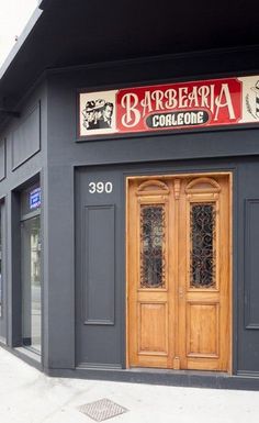 a building with two wooden doors on the side of it and a sign that says barbeqla colloone