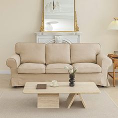 a living room with a couch, coffee table and mirror on the wall above it