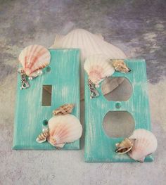 two seashells are sitting on a light switchplate in front of a sea shell