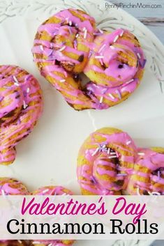 valentine's day cinnamon rolls with pink icing and sprinkles on a white plate