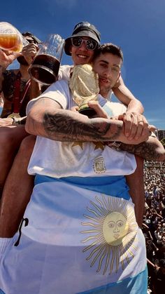 two men hugging each other in front of a large group of people at an outdoor event