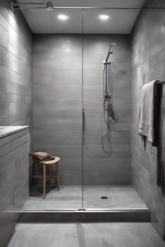 Modern, minimalist bathroom with a walk-in shower, gray tiles, rain showerhead, and wooden stool. Luxurious Spa, Wet Room