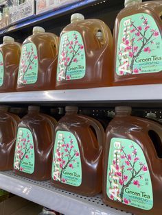 several gallon jugs of green tea sit on the shelf in a grocery store aisle