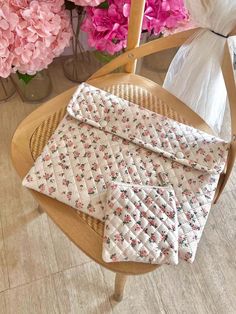 two pieces of cloth sitting on top of a wooden chair next to pink and white flowers