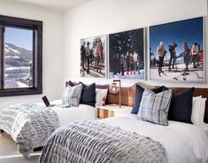 two beds in a room with pictures on the wall above them and below them is a window