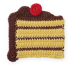 a crocheted yellow and brown cake with a red cherry on it's top