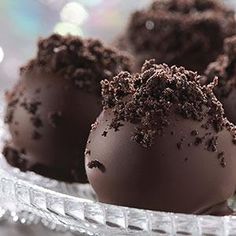 four chocolate truffles on a glass plate with some frosting and sprinkles