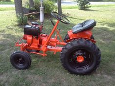 an orange tractor sitting in the grass