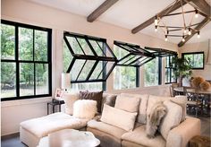 a living room filled with furniture and windows covered in lots of light fixture shades on the ceiling