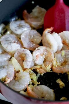 shrimp being cooked in a skillet with a red spatula