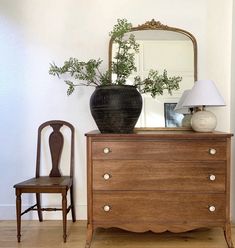 a wooden dresser sitting next to a chair