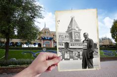 a hand holding up an old photo of a man standing in front of a building