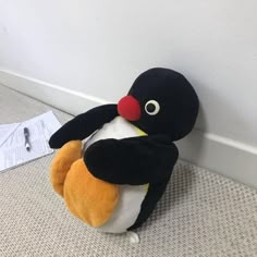 a stuffed penguin sitting on the floor next to a wall