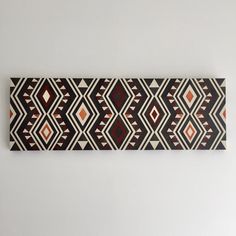 an art piece hanging on the wall in front of a white wall with a black and red pattern