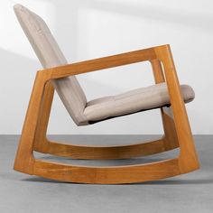 a wooden rocking chair sitting on top of a gray floor next to a white wall