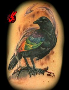 a tattoo with a bird on it's arm and an orange, green, yellow and blue tail