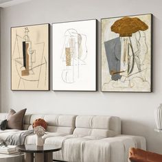 three paintings hang on the wall above a couch in a living room with white furniture