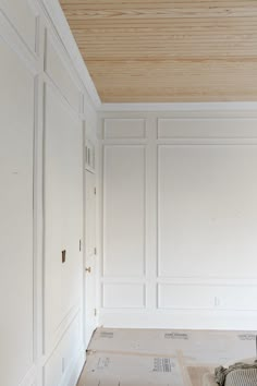 an empty room with white walls and wood ceilinging in the process of being painted