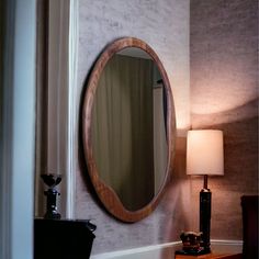 a mirror sitting on top of a wooden table next to a lamp and a dresser