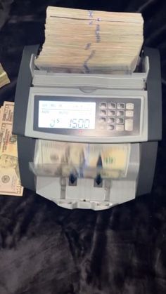 a machine that is sitting on top of some paper money and it has stacks of cash in front of it