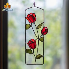 a stained glass window with three red roses hanging from it's side and green leaves on the outside